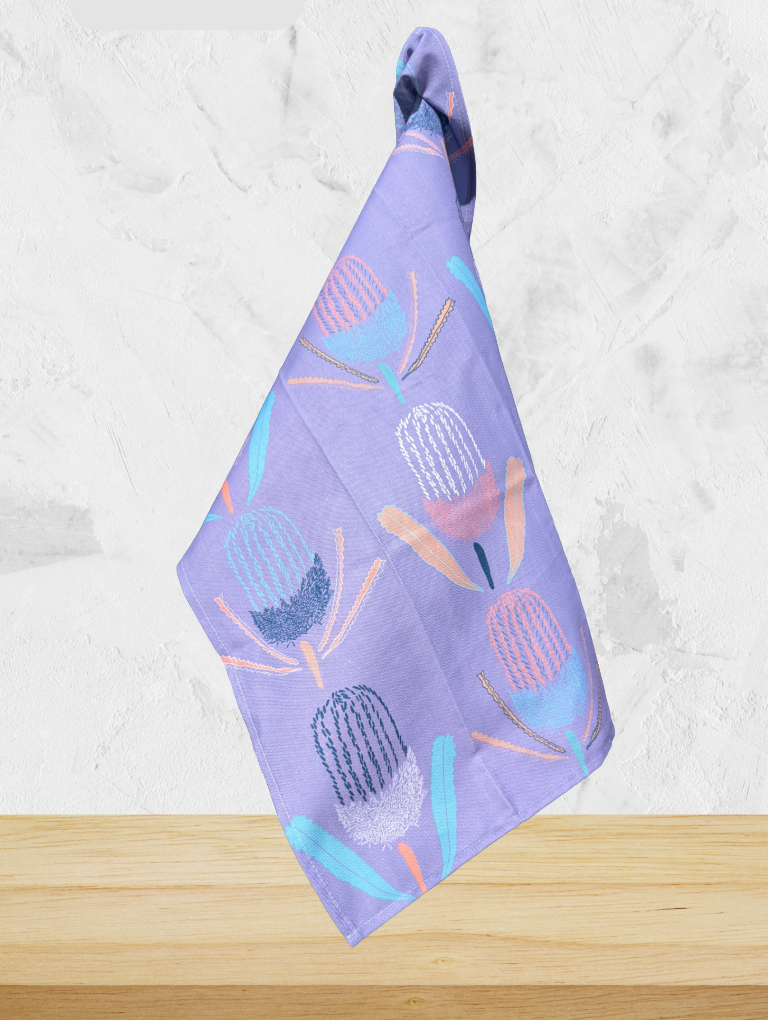 Purple towel with floral pattern on a wooden surface and light gray background
