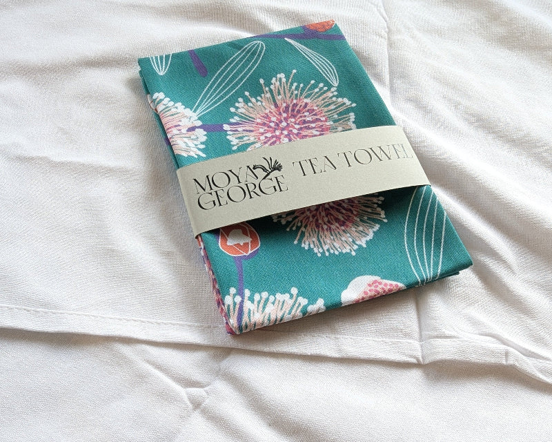 Floral tea towel with brand label on a white surface