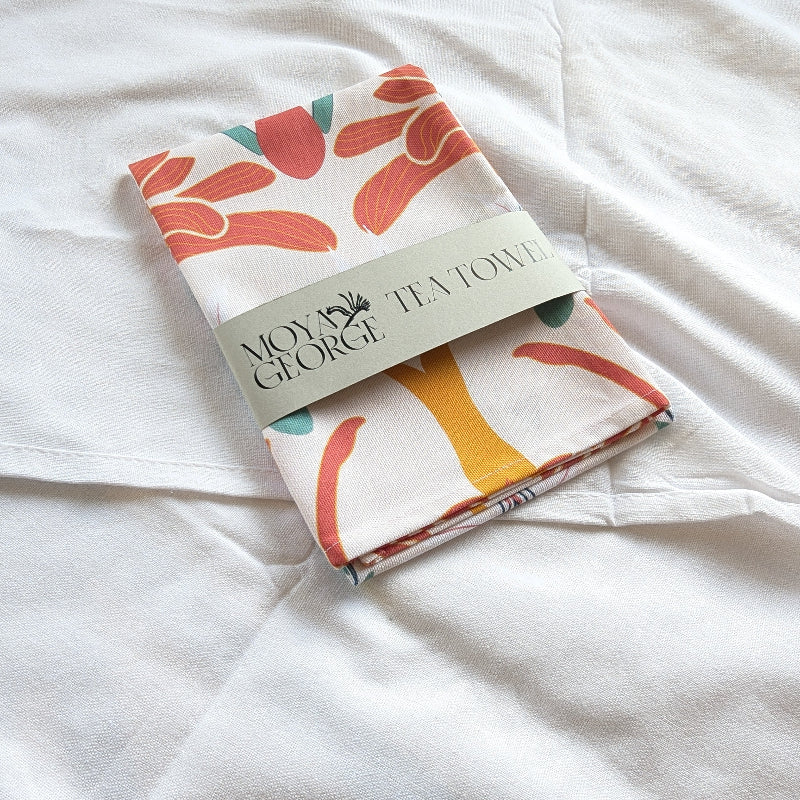 Folded tea towel with colorful leaf pattern on a white surface