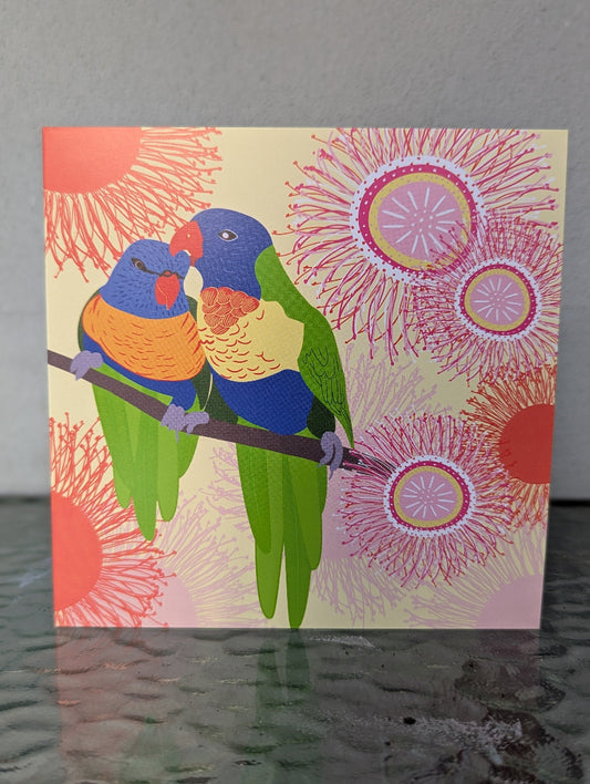 Card with two colorful parrots on a branch against a floral background