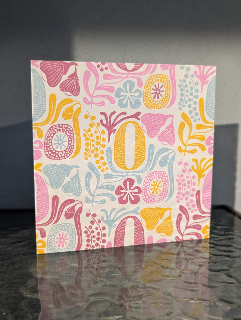 Colorful floral-patterned card on a reflective surface with a dark background