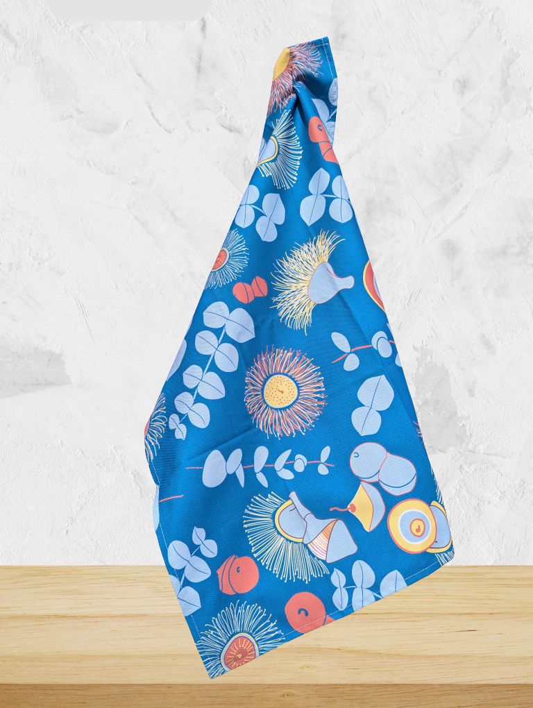 Blue fabric with colorful nature-themed pattern on a white marble surface